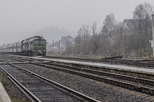 Yasinya, Ukraine. March 17, 2024. cloudy rainy sky. an incredibly beautiful view of the fog-shrouded mountains. a train with people arrived at the platform.