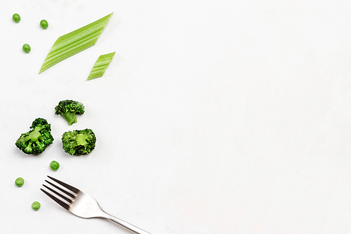 Fork, broccoli and celery stalks on white background. Menu background. Copy space. Flat lay