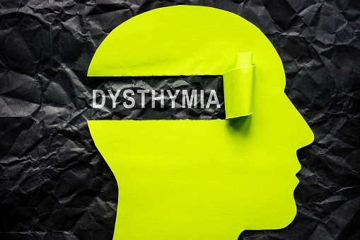 Paper head on crumpled surface and the word dysthymia.