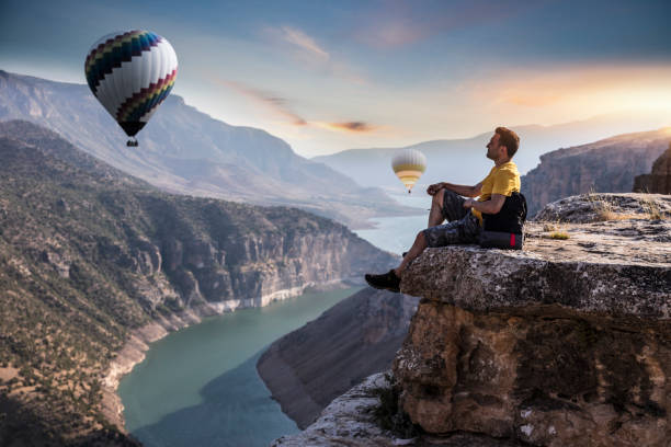 Backpacker watching hot air balloon flying over the Botan Canyon in TURKEY