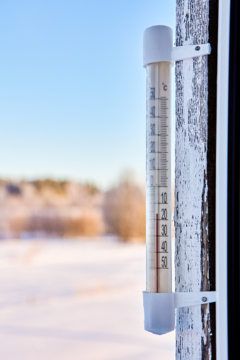Outdoor thermometer reads 16 degrees below zero Celsius,  thermometer is secured to wooden window frame using upholstery nails.