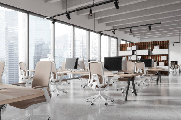 istock Modern office coworking interior with pc monitors and chairs in row, window 2128281178