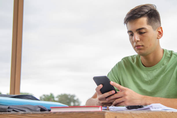 portrait of young latin college happy handsome university male student, doing homework with a spectacular view of a lake in university campus outside the library. - library student latin american and hispanic ethnicity university stock-fotos und bilder