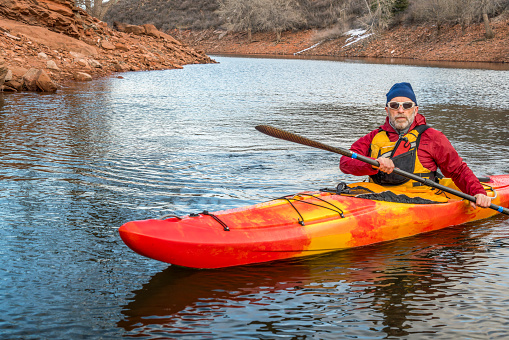 senior male paddler is paddling colorful river kayak on a calm lake  - recreation concept, cold season on Horsetooth Reservoir in Colorado - self portrait