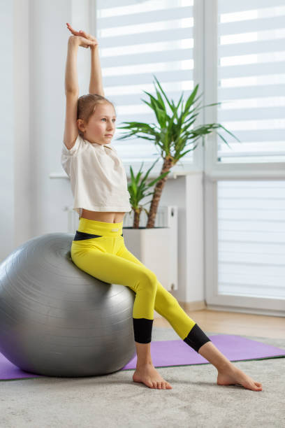 istock Child Stretching Arms Upwards While Seated on Ball 2128439528