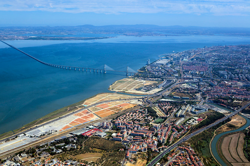 Lisbon, Portugal: aerial view of the Mar da Palha (Sea of Straw) inland sea in the Tagus River estuary, the eastern area of Lisbon and the Montijo / Alcochete on the southern bank, connected by the Vasco da Gama bridge. Below the bridge, the River Trancão can be seen, meandering towards its mouth, separating Bobadela from Sacavém. Above the bridge lie the Expo, Moscavide and Olivais areas. On the horizon is the south bank, with the Arrabida mountains and the Montijo Air Force base (BA6) on the top left, part of Setúbal district.