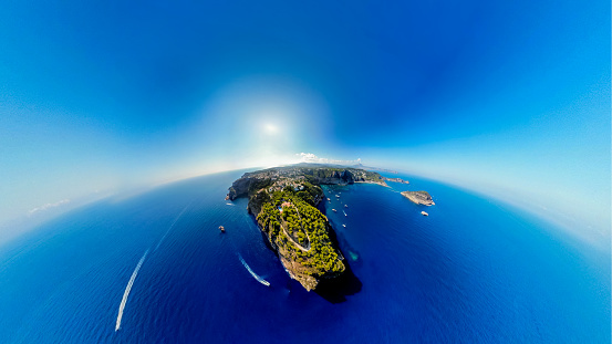 Experience the breathtaking beauty of Costa Blanca from a bird's eye perspective! This aerial image, captured with a drone, showcases the sparkling Mediterranean under radiant sunshine, the majestic steep cliffs, luxurious yachts, and a few small islands. With a 180-degree view, this picture offers a unique perspective of the world from above.