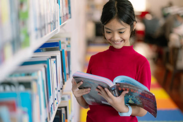 istock A young girl is reading a book in a library 2128519708