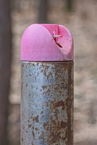 one gray metal spray can for paint in brown rust with a pink plastic sprayer on the street