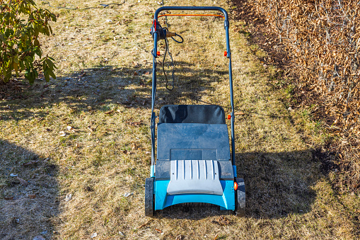 Close-up of an electric lawn aerator on the dry winter grass in the garden on a spring day. Sweden.
