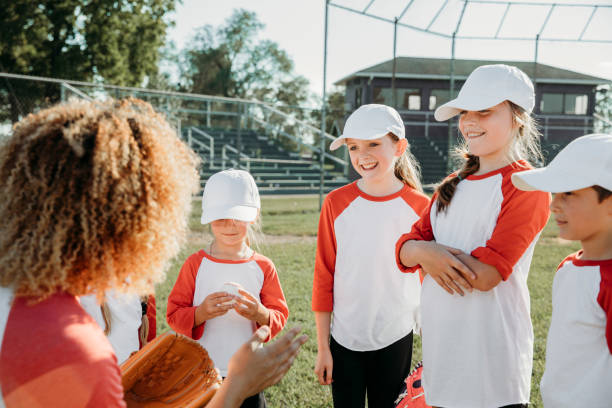 istock Young elementary school athletes participate in co-ed little league baseball, accompanied by coaches, at a ballfield 2128665449
