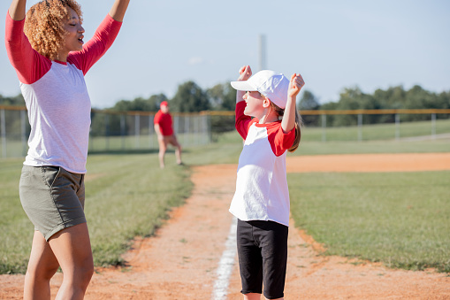 At the heart of the ballfield, a co-ed little league baseball team consisting of elementary school children, under the mentorship of coaches, showcases their talent and enthusiasm