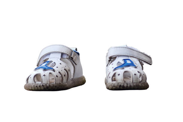 Pair of white sandals on the pavement, isolated on white background. Selective focus, isolated on white background.