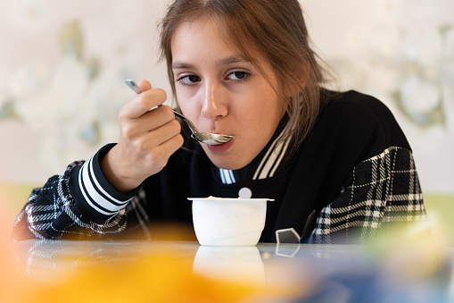 Close-up of a woman eating a yogurt. Children eat dairy products. The benefits of dairy products for children