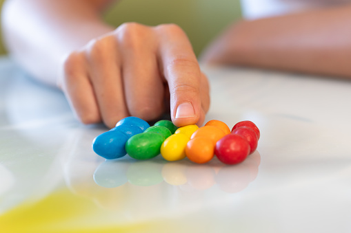 Amazed sweet-tooth. Beautiful child girl holding colorful chocolate drops,