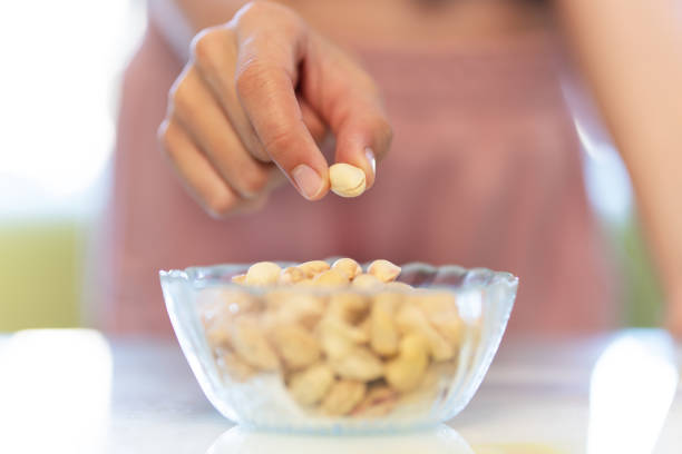 istock pistachios nuts in dish. Illuminated by natural light. A woman's hand takes a pistachio from a plate. 2128672921