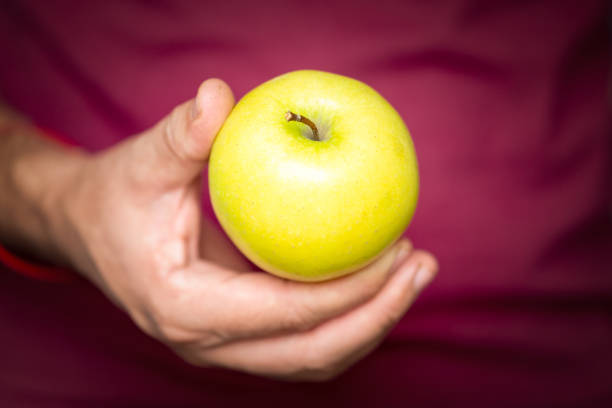 Man's hand holds an apple, snack and fast food concept.