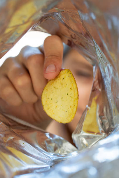 istock Hand picking potato chips inside snack bag. open pack of chips. 2128674008