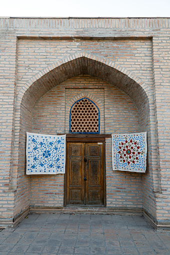 small carpets hang on the wall in front of the entrance to the souvenir shop in Samarkand, Uzbekistan.