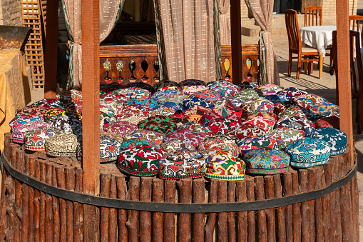 a lot of colorful beautiful skullcaps on a table at a street bazaar in the old city of Khiva, Khorezm region, Uzbekistan.