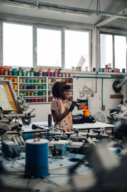 istock Interracial printing shop worker mixing paint while standing at factory 2128683270
