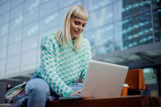 istock An e-nomad is sitting on street downtown and typing on a laptop. 2128683811