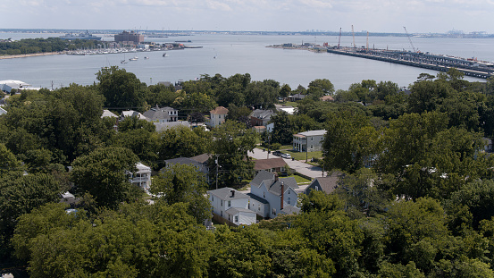 Houses tucked away in tree area stand against water bay in Phoebus, Hampton, Virginia. Fort Monroe in the distance