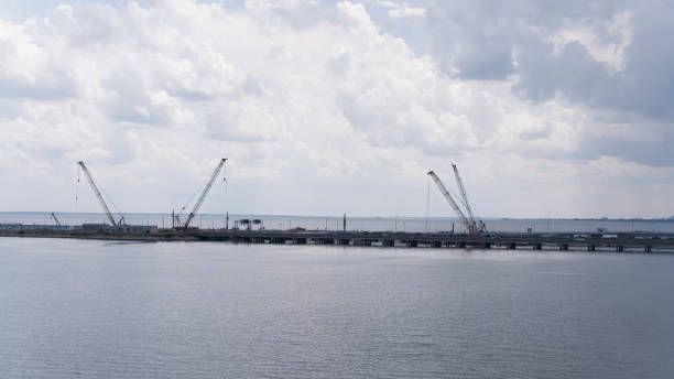 istock Construction of bridge and tunnels with gantry cranes under cloudy sky in Hampton, VA. Aerial view 2128703553
