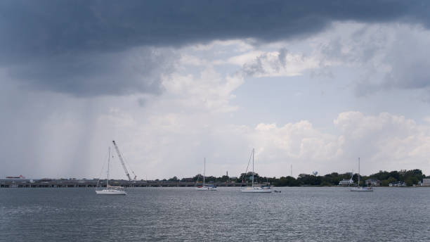 폭풍 전의 arcus 구름이 강 다리 옆의 보트를 덮습니다. 갠트리 크레인과 phoebus 스카이 라인은 버지니아 주 햄프턴 로드의 흐린 하늘 아래 있습니다. - sailboat pier bridge storm 뉴스 사진 이미지