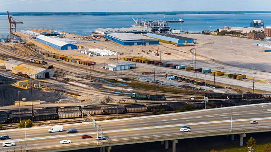 Freight transit and transportation in harbor. Hampton Roads Beltway traffic alongside industrial port in Newport News, VA. Aerial view