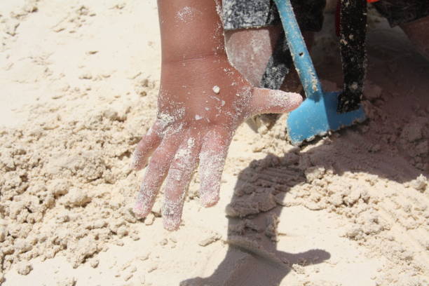 istock Child's hand playing with the beach sand. 2128721606