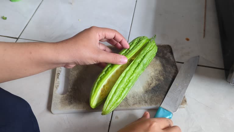 Cutting green bitter gourd vegetables on white cutting board