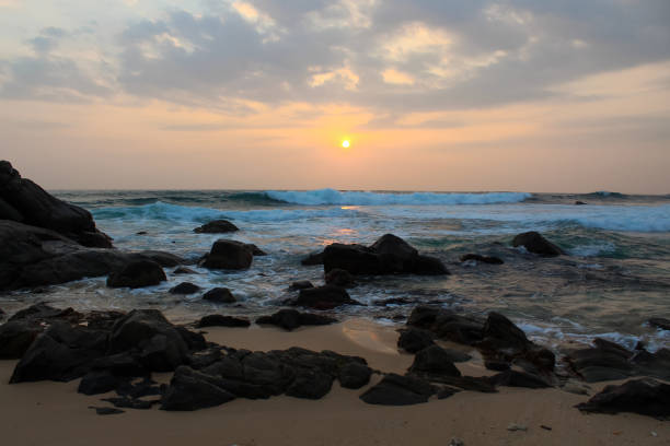 the sun setting into the sea at delawella beach, sri lanka. golden light - asia forest sri lanka rock ストックフォトと画像