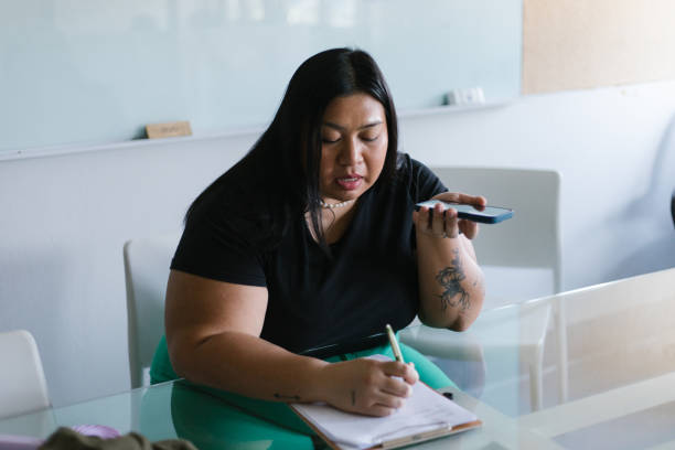 Woman Using Speakerphone To Work In Office