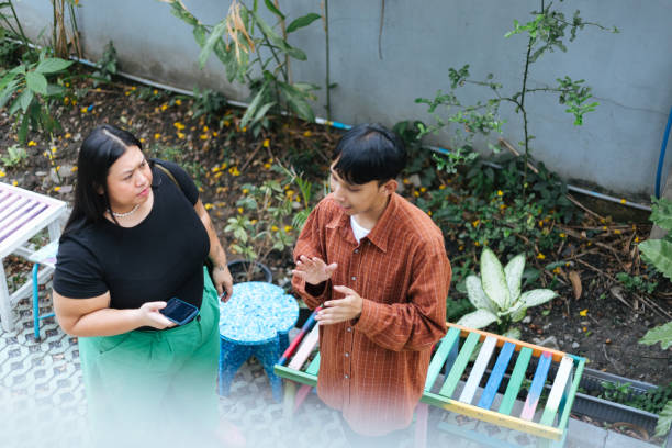 Colleagues meeting outside of sustainable park with recycled plastic benches discussing and taking notes on phone.