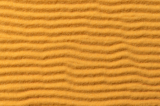 Bright wavy sandy background. Clean sea sand.