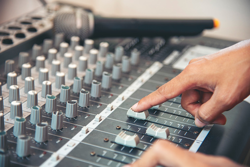 Production sound engineer woman hands adjusting volume equalizer voice, mixing console. DJ sound engineering working on recording studio mixing voice control.  Producer remix tune music sound record