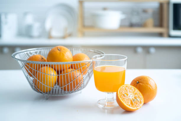 オレンジフルーツとオレンジジュースのグラスは、家庭のキッチンで朝食のテーブルの上にあり、選択的焦点です