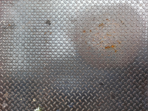 Olld worn grungy metal diamond plate pattern. Metallic industrial non-slip steel tread repetitive diagonal oval shape pattern, embossed steel surface