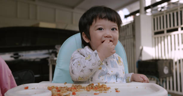 istock Asian boy eating food at home. Kid learning  using hand. 2129064799