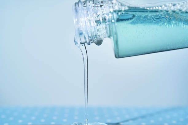 istock Cosmetic bottle from which serum is pouring on a blue background. 2129080092