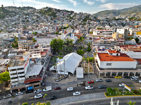 View of Acapulco's Zocalo with vibrant urban life against hillside homes, after otis