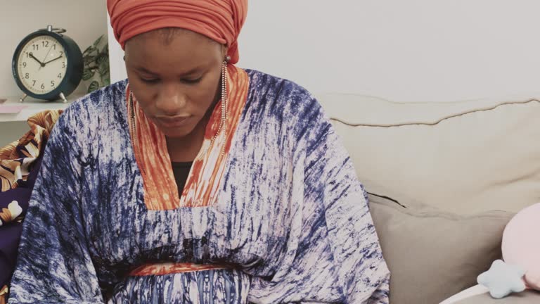 African muslim woman reading a book in the living room