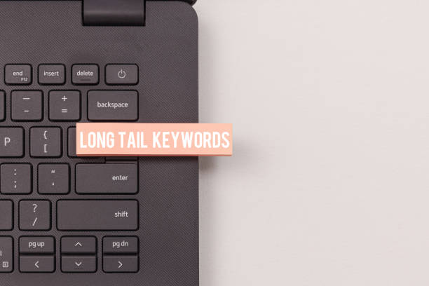 close-up view of laptop keyboard highlighting long tail keywords concept - tail long marketing internet imagens e fotografias de stock