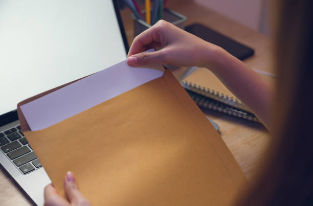 istock Close up of hand holding paper envelope and opening paperwork on table. 2129270611