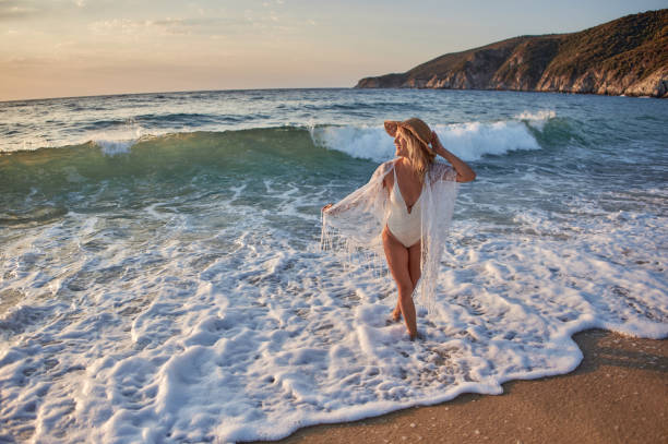 istock Beautiful woman running inside water on the beach at sunset 2129273765
