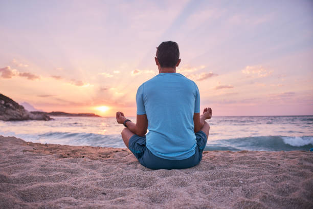 istock Man on the beach doing yoga at sunset 2129275489