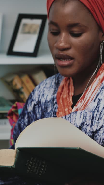 Black woman reading book on sofa