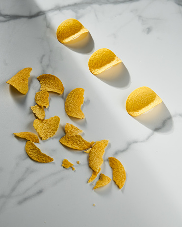 Golden and crusty potato chips on white marble background. Minimalistic food photo. High quality photo