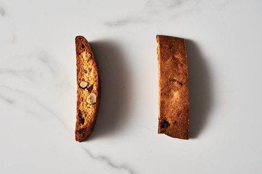 Two Pieces of Almond and Cranberry Biscotti Standing on Marble Counter, Shadowed with Natural Light. High quality photo
